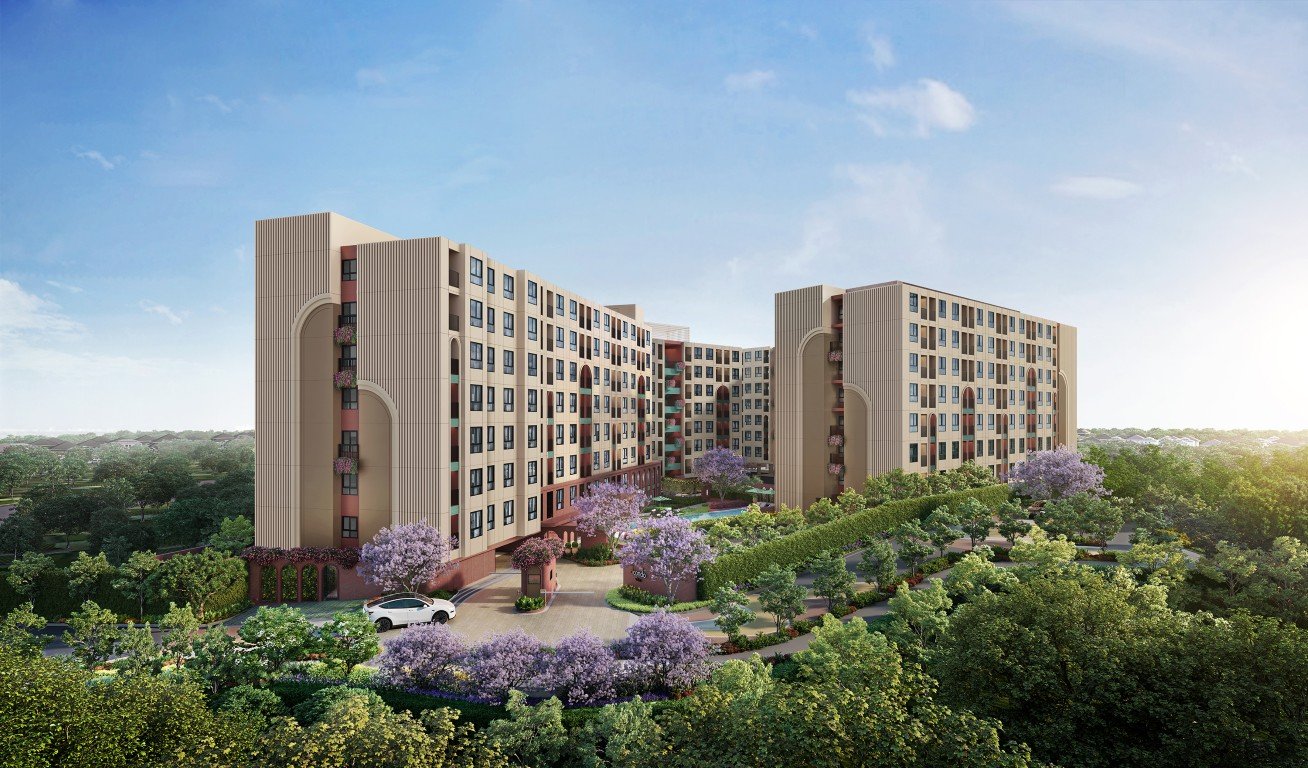 Modern beige apartment complex with curved towers surrounded by lush landscaping and flowering trees a driveway and car at the entrance