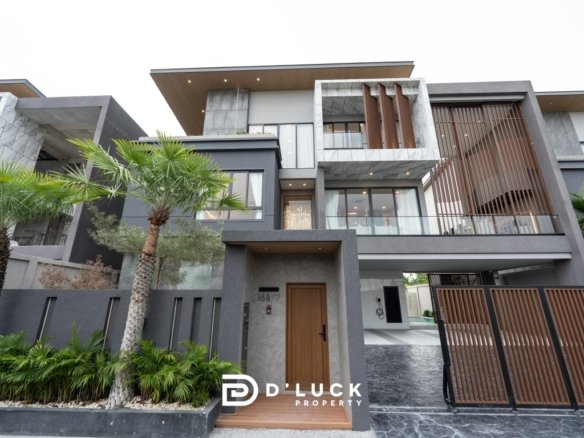 Modern gray multi level house with wooden accents metal gate and palm trees DLuck Property logo visible at bottom