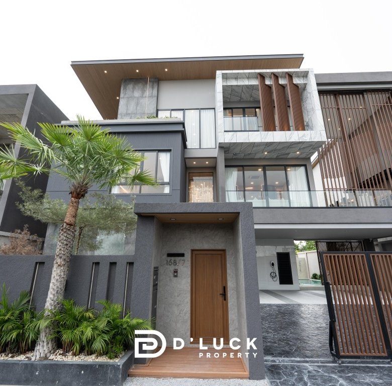 Modern gray multi level house with wooden accents metal gate and palm trees DLuck Property logo visible at bottom