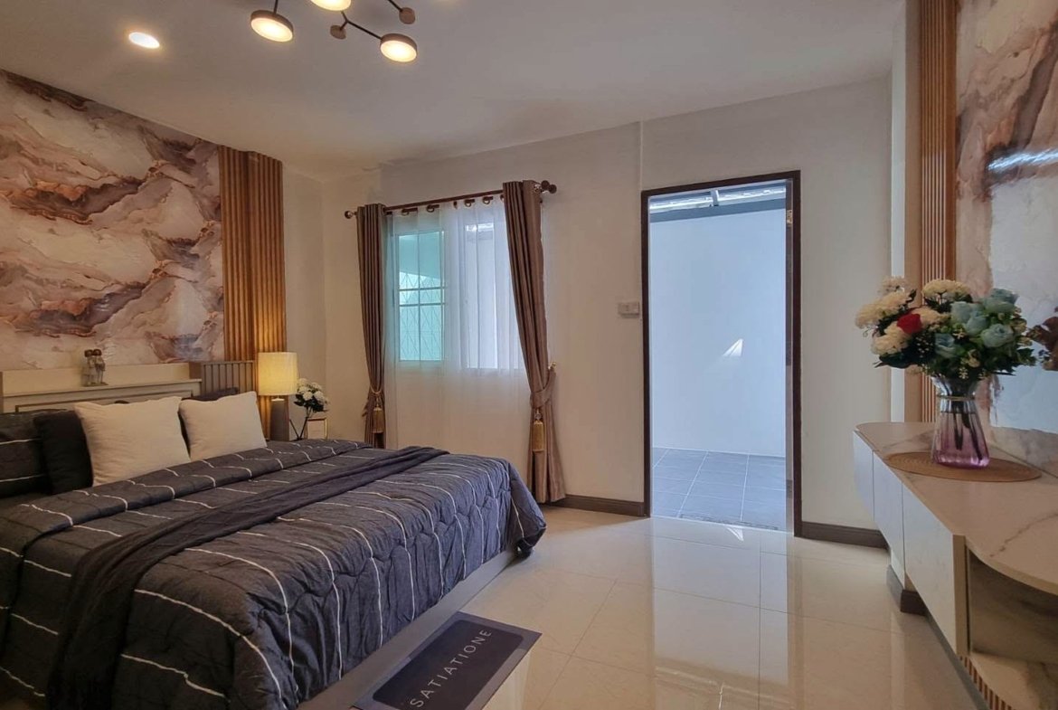 King bed with dark gray quilt and white pillows, marble-patterned walls, and warm bedside lighting in a modern bedroom