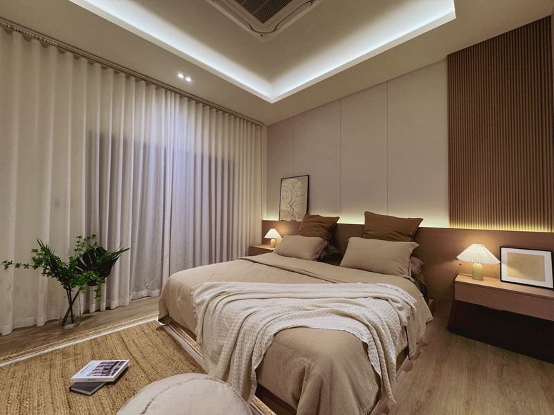 Contemporary bedroom with a large bed, beige bedding, and soft bedside lamps on each side.