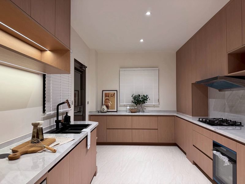 Modern L-shaped kitchen with light wood cabinets, white countertops, and a gas stove on the right.