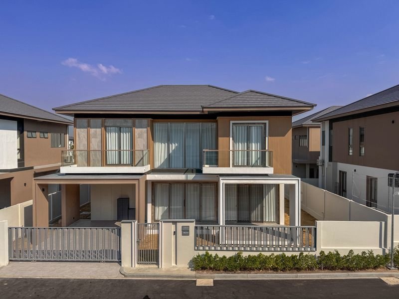 Modern two story townhouse with glass balcony doors gated front yard and neighboring homes on each side