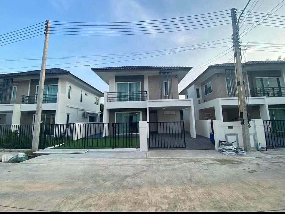 Three modern twostory houses with gated driveways and small front lawns on a sunny residential street