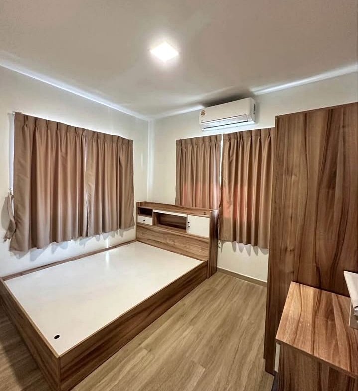 Wooden bed frame with built-in headboard and storage in a tidy, wood-toned bedroom; two brown curtains, wardrobe, and floor-wide space.