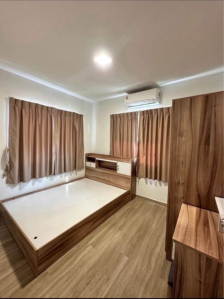 Wooden bed frame with built-in headboard and storage in a tidy, wood-toned bedroom; two brown curtains, wardrobe, and floor-wide space.