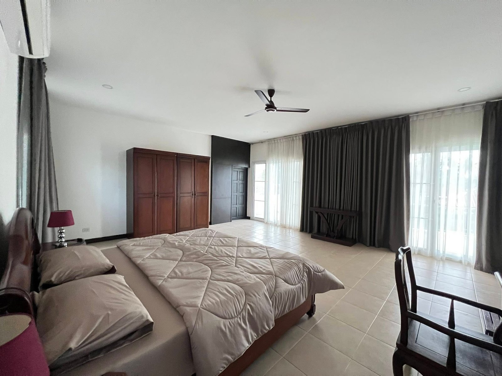 House_Sale_Mabprachan_Pattaya_Dlh533_21 Spacious bedroom with two large beds, dark wood wardrobe, and ceiling fan in a bright, modern room.