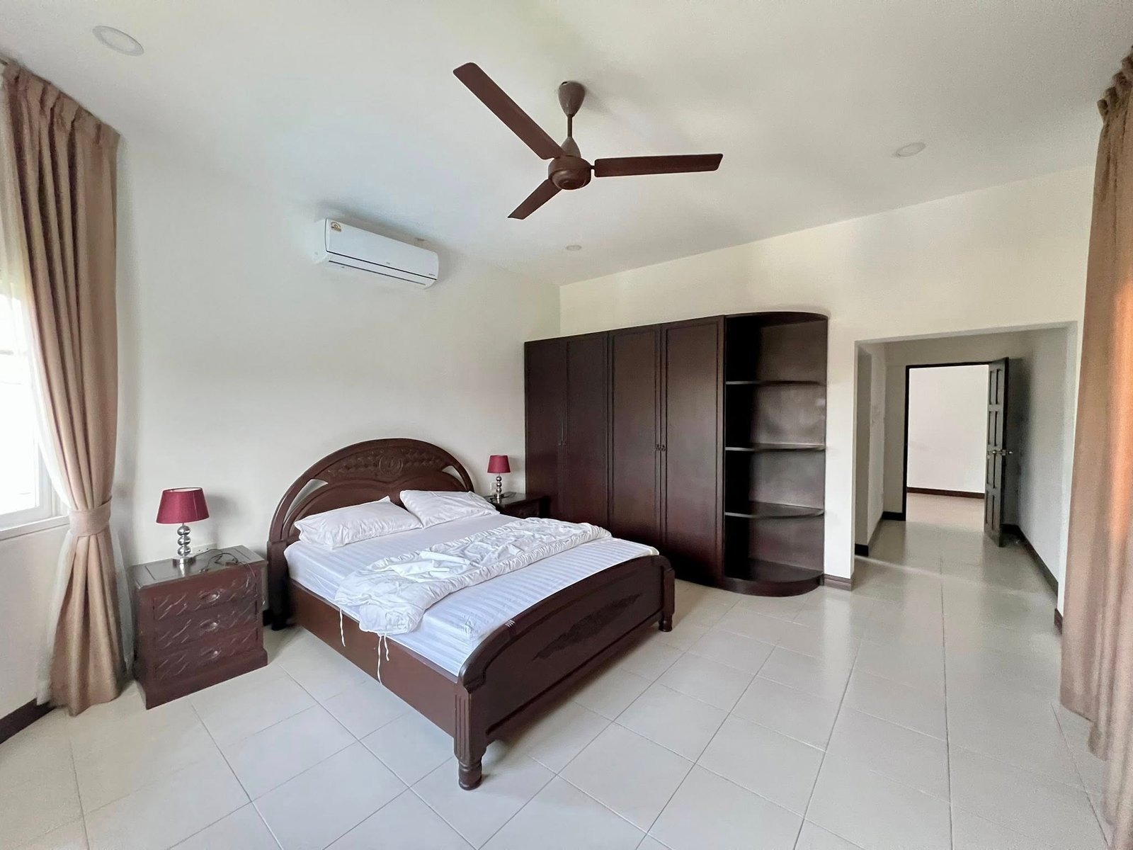 House_Sale_Mabprachan_Pattaya_Dlh533_5 Dark wood bedroom with a large bed, matching nightstands, built-in wardrobe, white bedding, and a ceiling fan.
