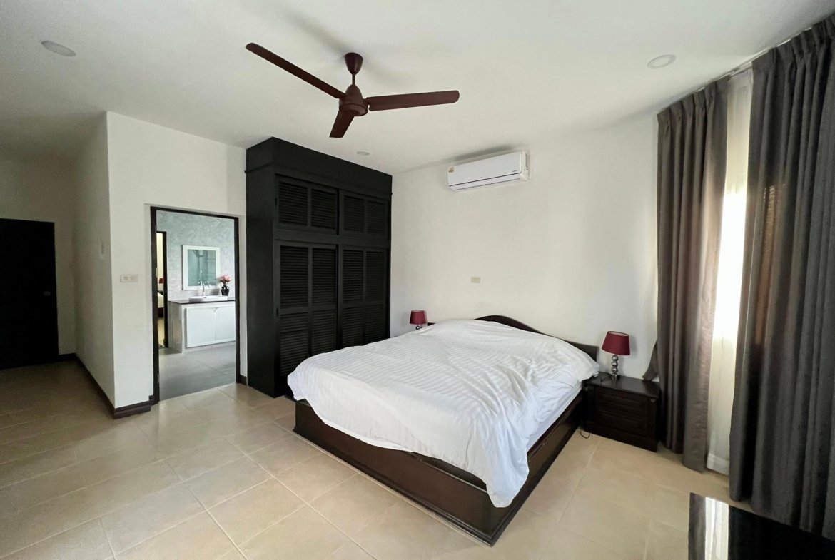 Bedroom with a large dark wood bed frame, white bedding, and matching nightstands with red lamps
