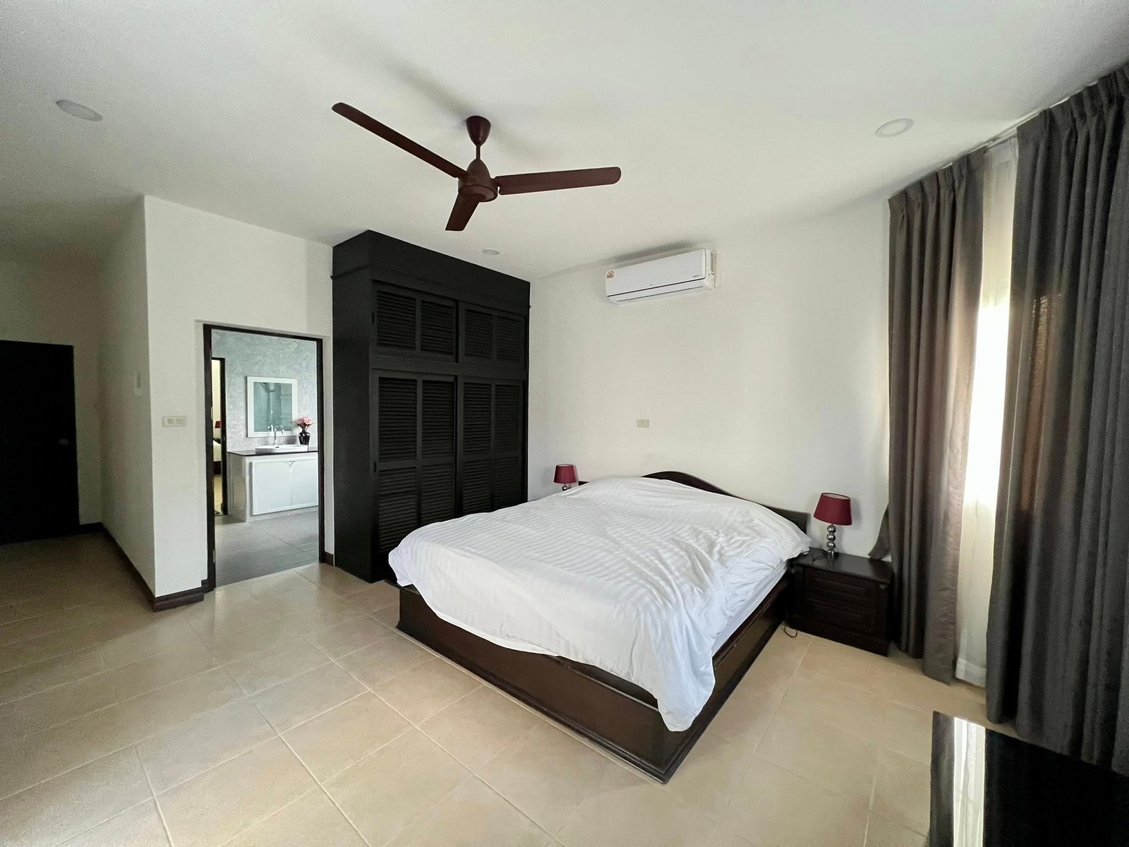 House_Sale_Mabprachan_Pattaya_Dlh533_6 Bedroom with a large dark wood bed frame, white bedding, and matching nightstands with red lamps