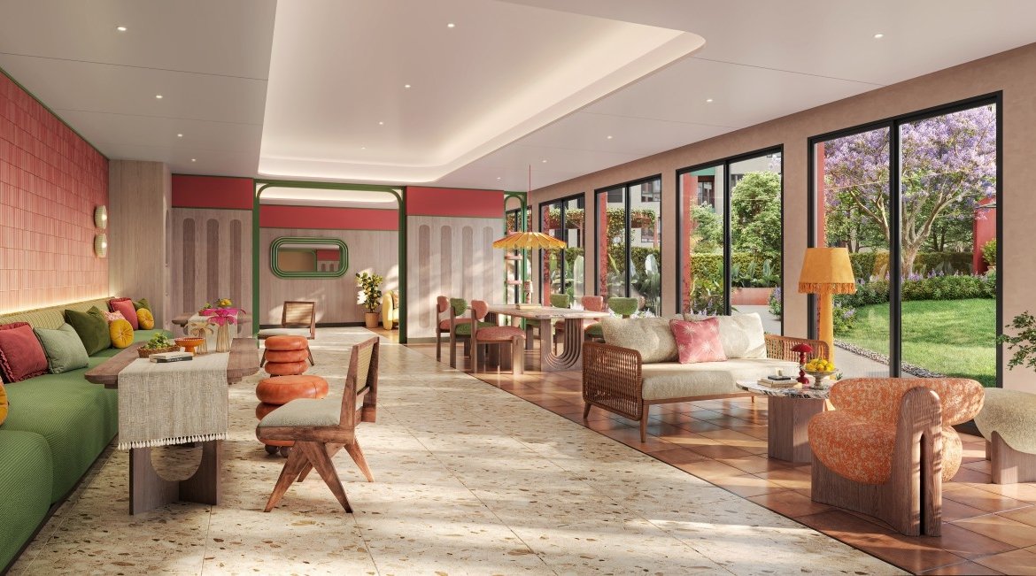Bright, inviting lounge with a green sofa and colorful cushions beside large windows that overlook a garden.