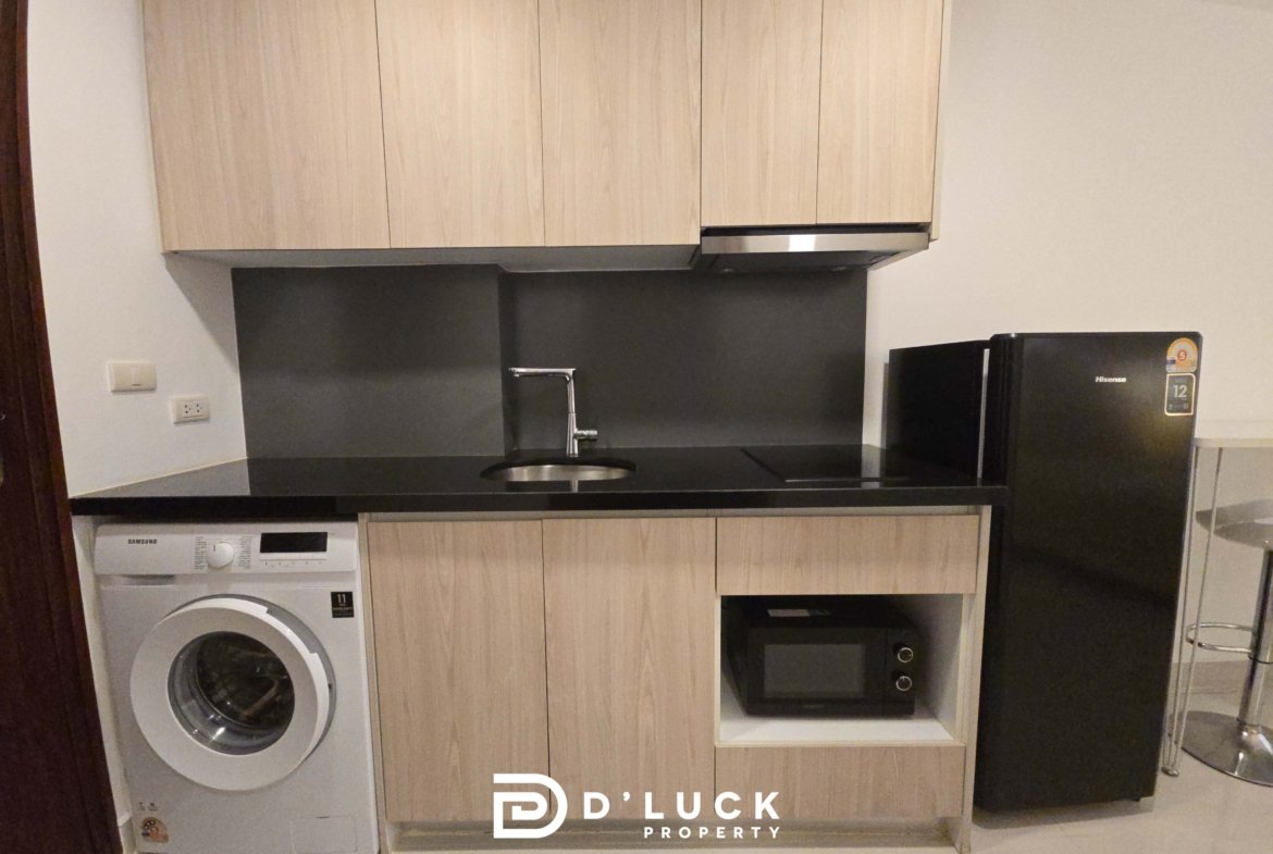 Kitchen with light wood cabinets, black countertop, sink, and built-in appliances including a washing machine on the left and a fridge on the right; watermark at bottom says 'D Duck Property'