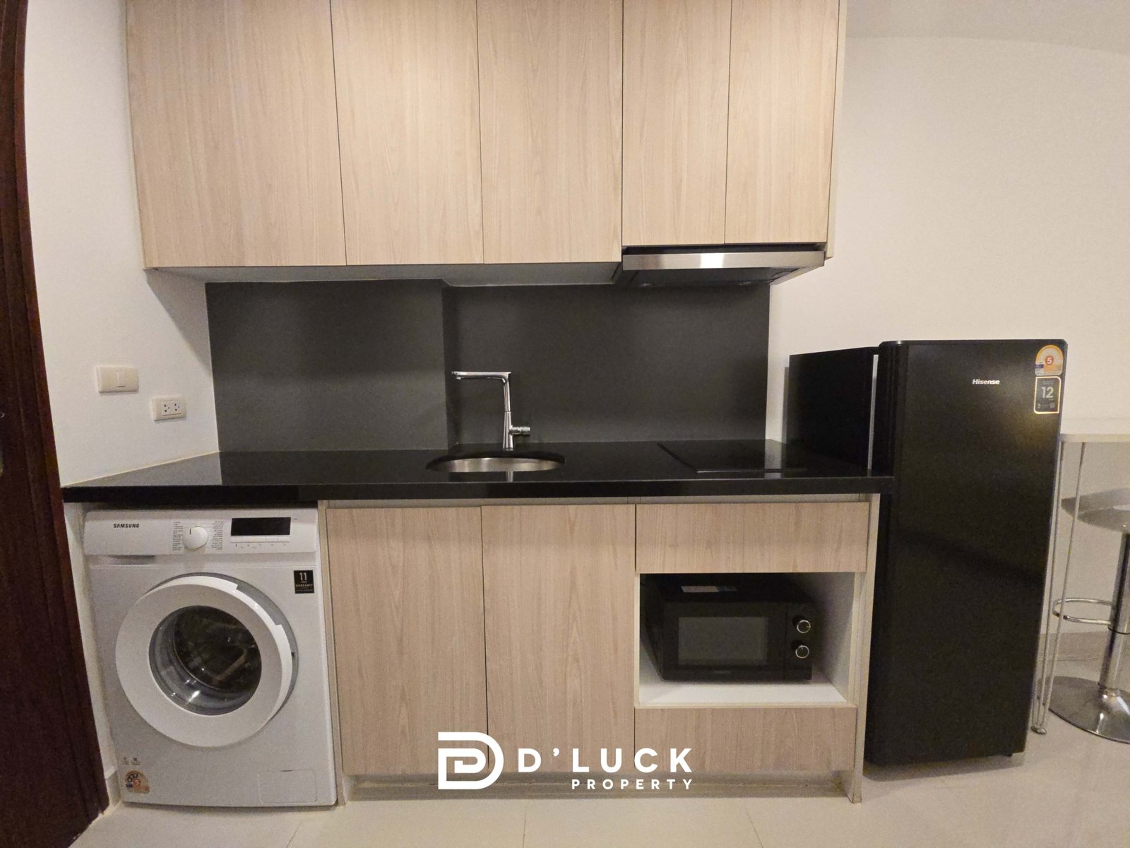 Kitchen with light wood cabinets, black countertop, sink, and built-in appliances including a washing machine on the left and a fridge on the right; watermark at bottom says 'D Duck Property'