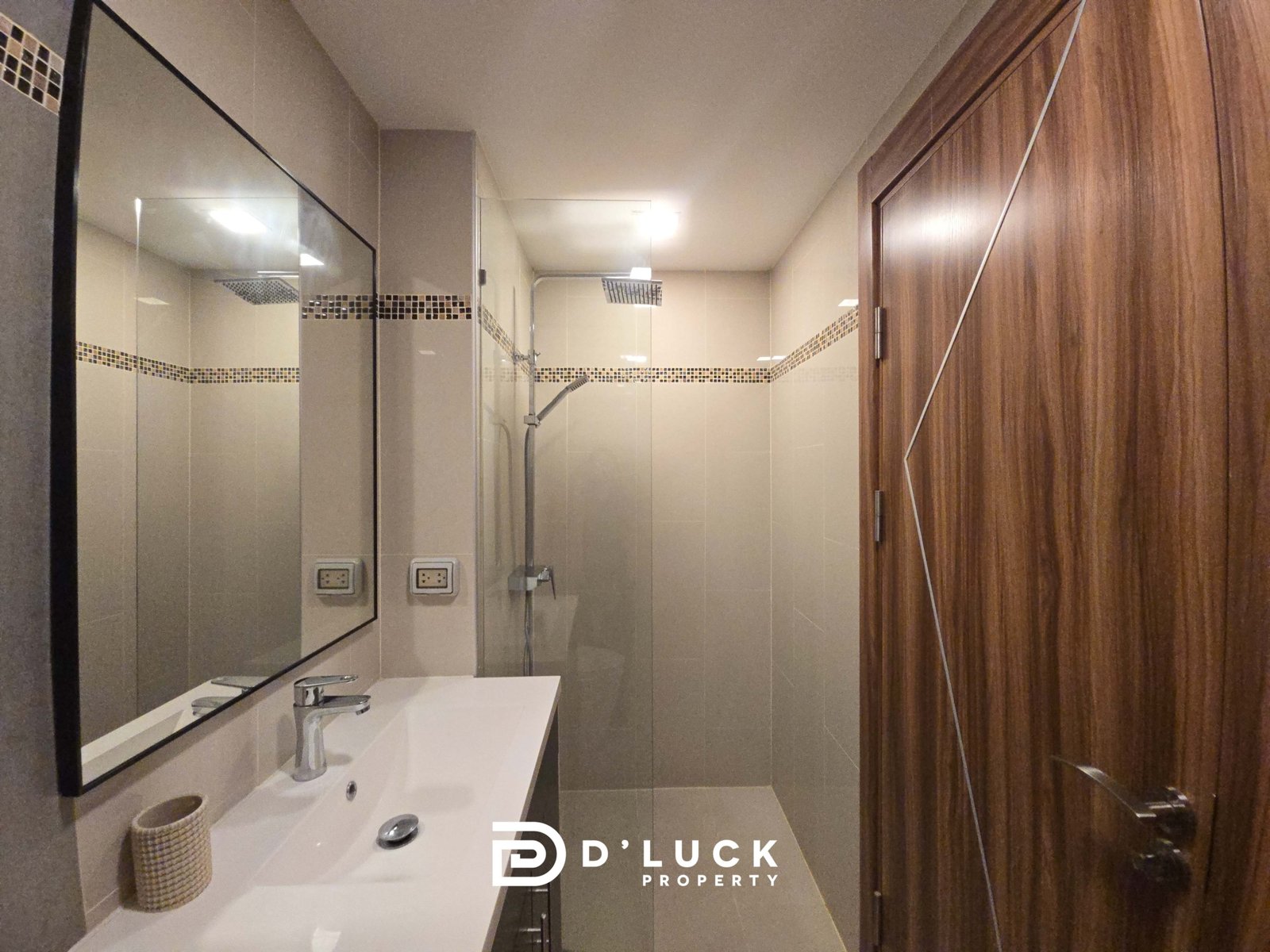 Modern bathroom with a white double sink, large wall mirror, glass shower, and mosaic tile accent strip.