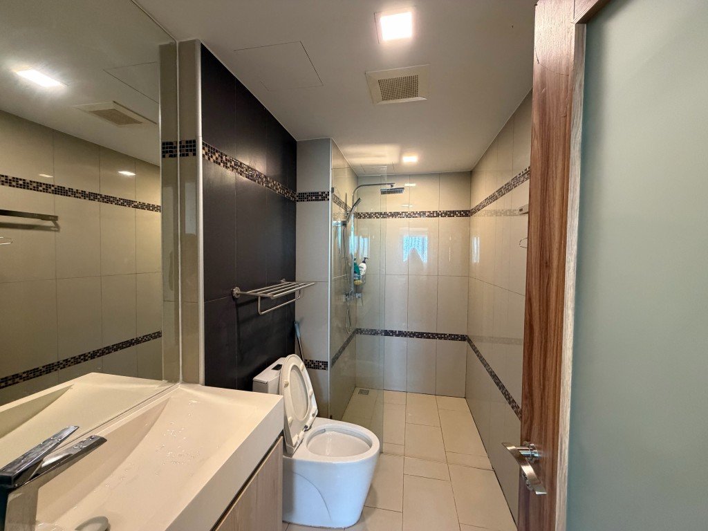Modern bathroom with walk-in shower, glass partition, sink, and toilet seen from the doorway.