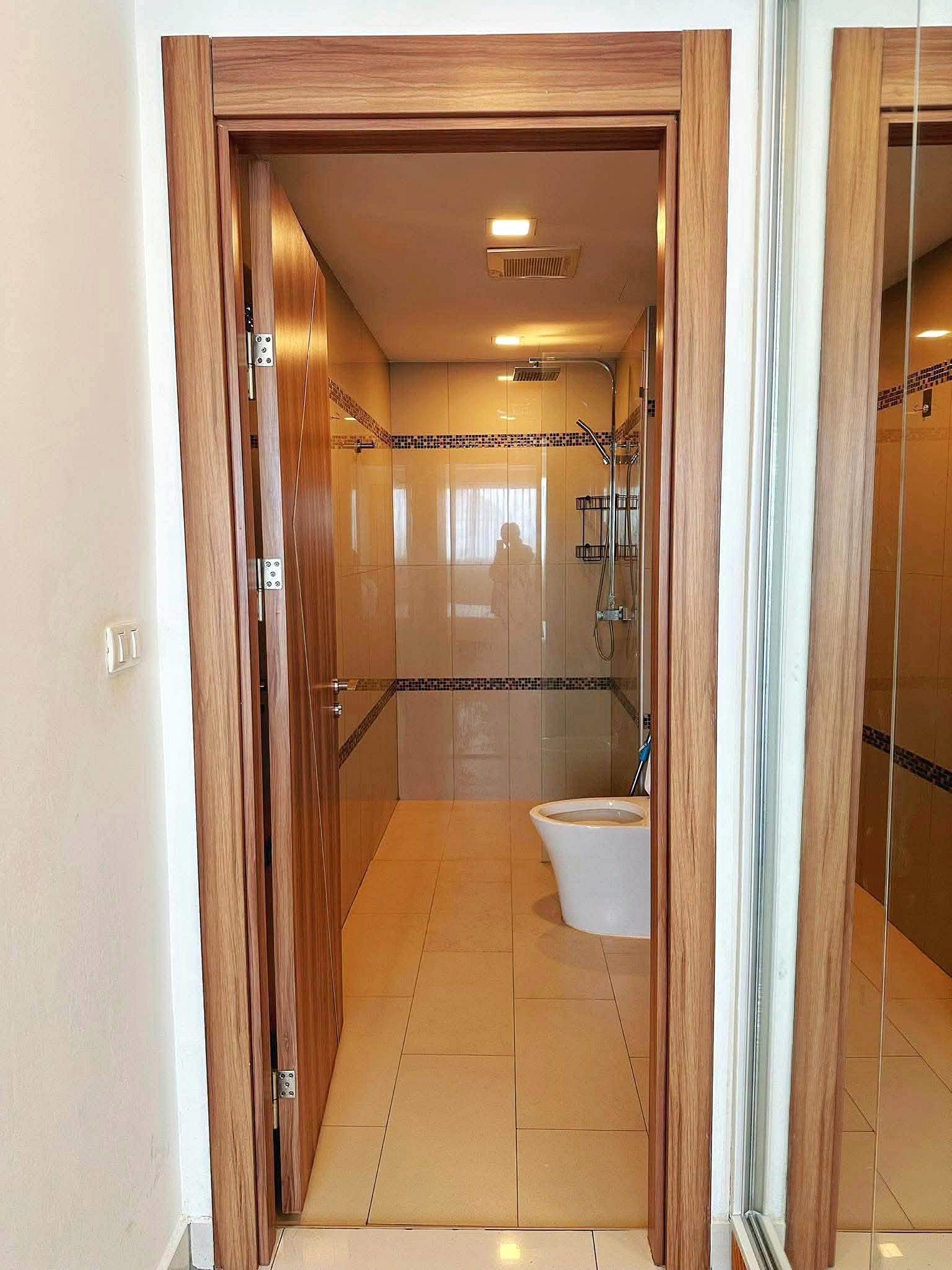 Laguna_2_Pattaya_Sale_Dlc636_7 Open doorway into a beige-tiled bathroom with a glass shower enclosure and a white toilet at the entrance.