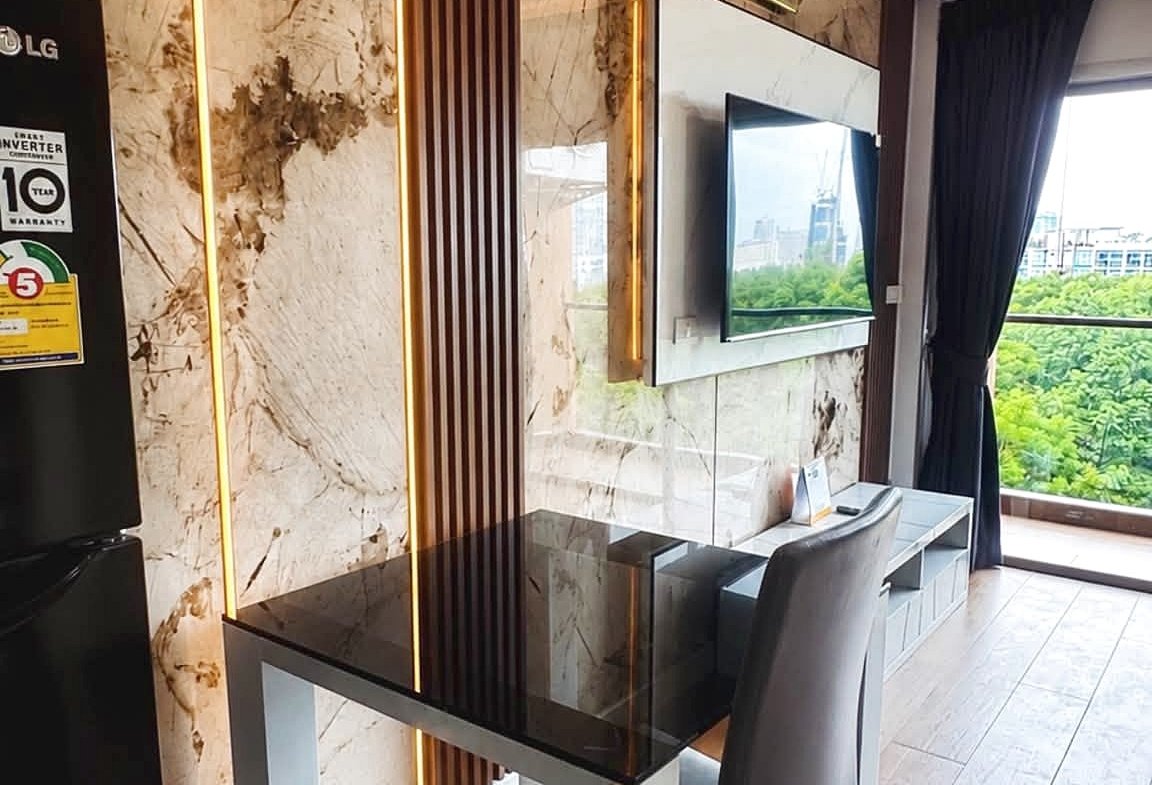 Modern living area with marble wall panels, vertical wood slats, and warm LED accents near a glass dining table and TV panel.
