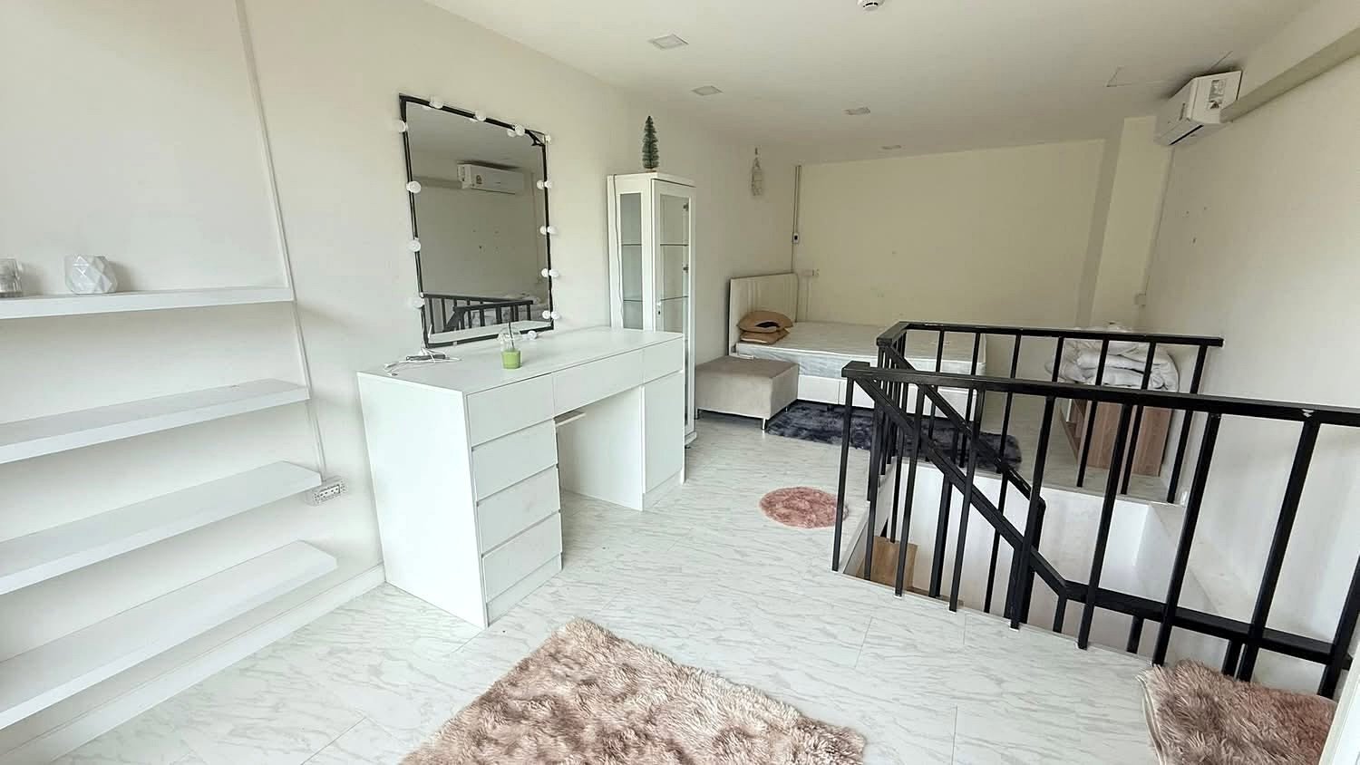 Laguna_Beach_2_Pattaya_Dlc627_3 Bright white loft room with a makeup vanity, mirror framed with bulbs, and a metal railing nearby.