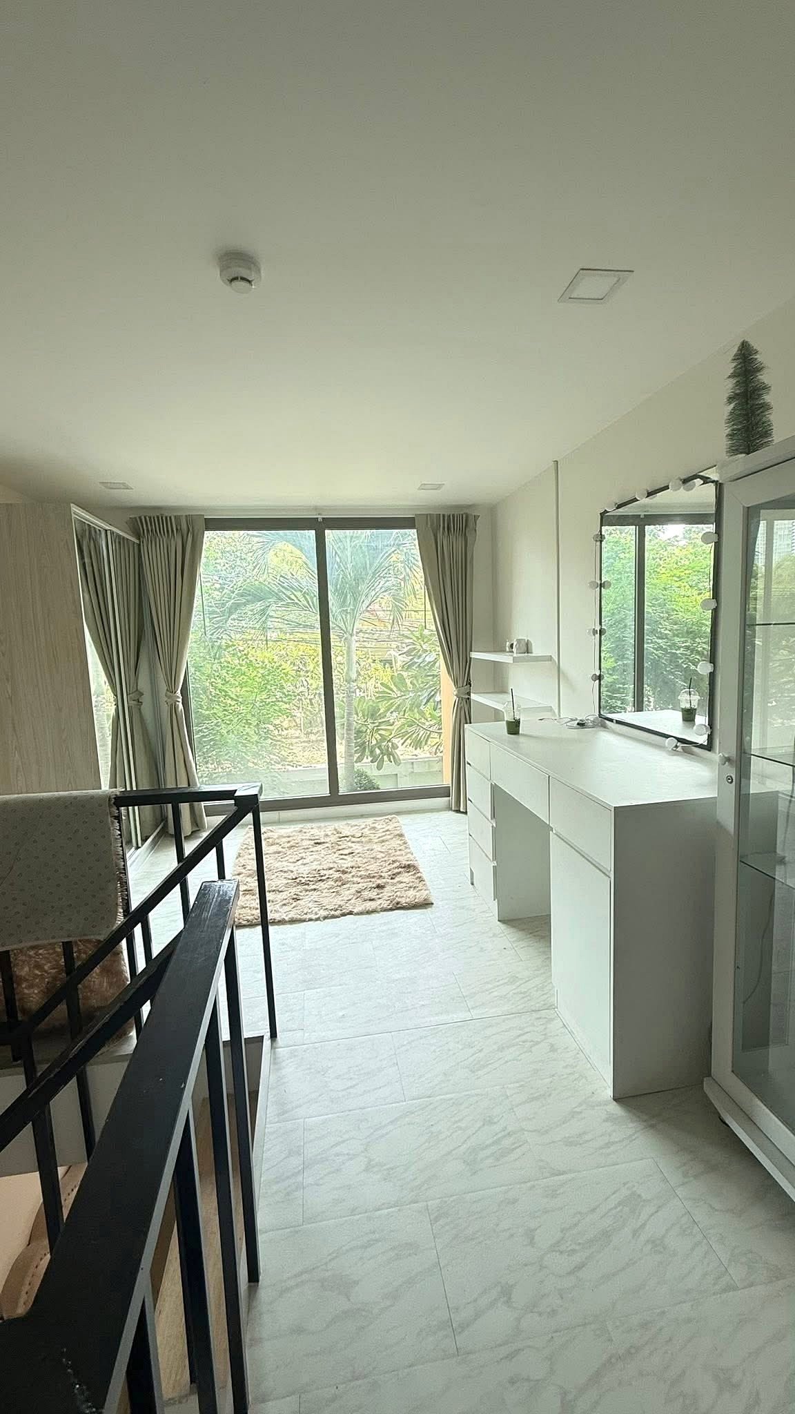 Laguna_Beach_2_Pattaya_Dlc627_4 Bright dressing area with a white dresser and illuminated mirror, marble floor, and large window with beige curtains.