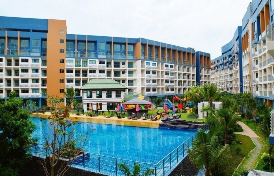 Resort style hotel courtyard with a large swimming pool lounge chairs and colorful buildings surrounding it