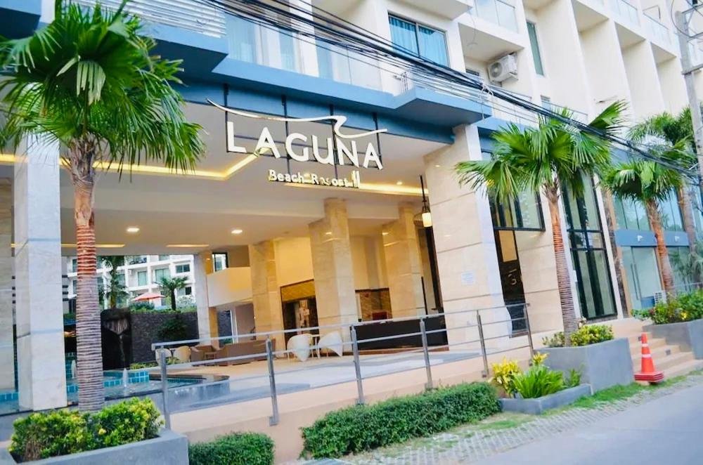 Entrance of Laguna Beach Resort with palm trees, outdoor seating, and glass doors under a porte-cochère.