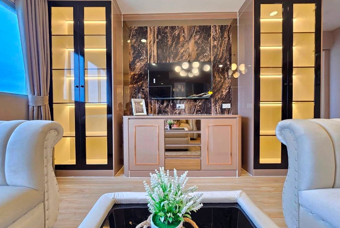 Luxurious living room with a marble feature wall, wall-mounted TV, and beige storage cabinet flanked by tall glass-display cabinets.