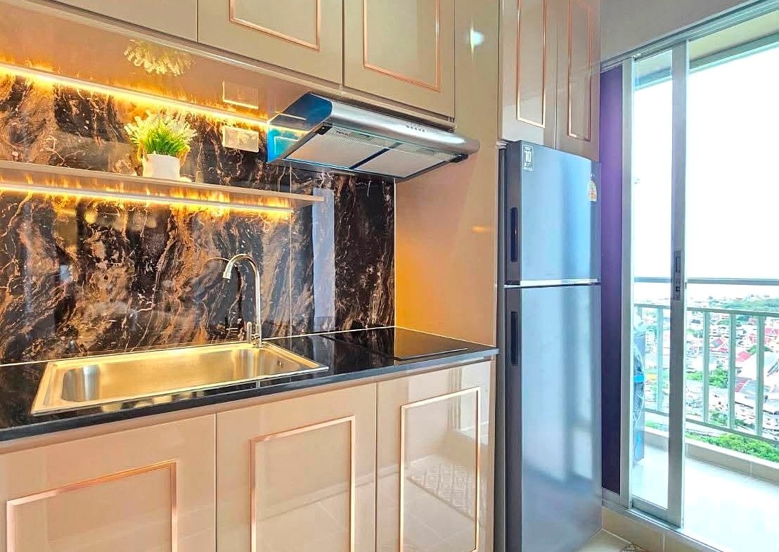 Modern kitchen with beige glossy cabinets, black marble backsplash, and stainless steel sink with a chrome faucet beside a sliding balcony door.