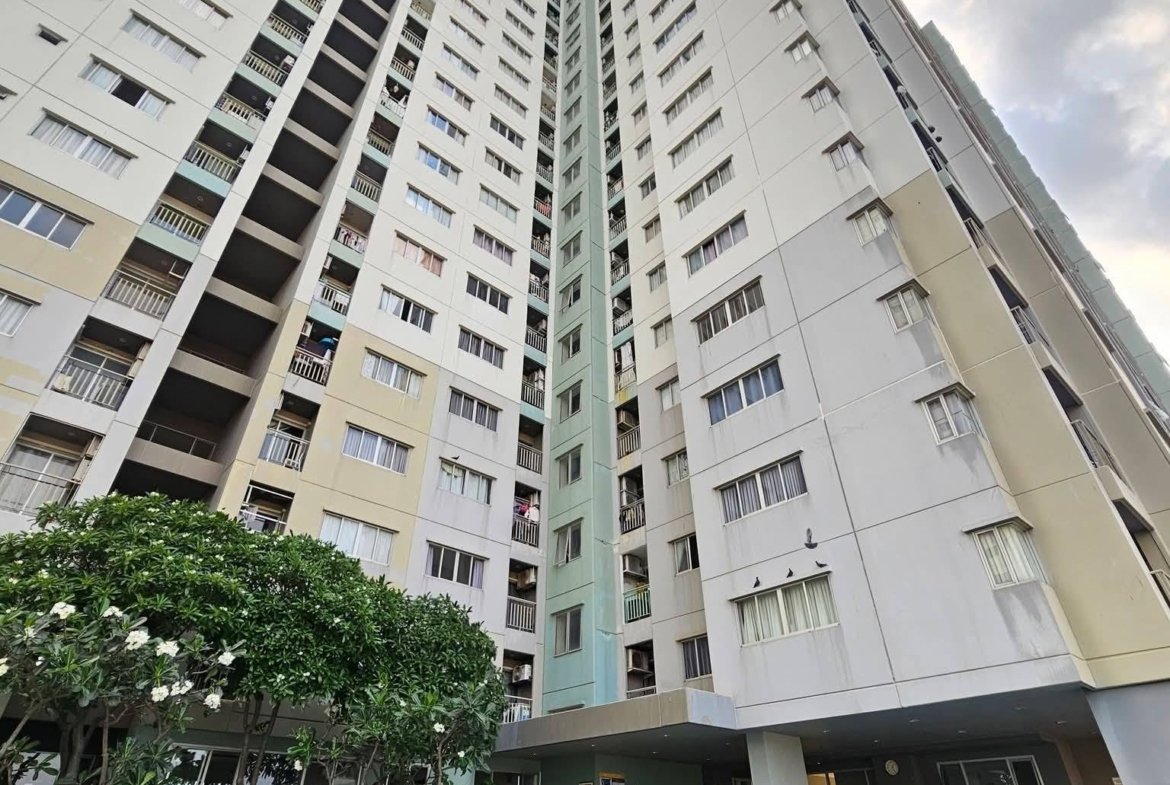 Tall residential high-rise buildings surround a courtyard pool with blue water and greenery in the foreground.