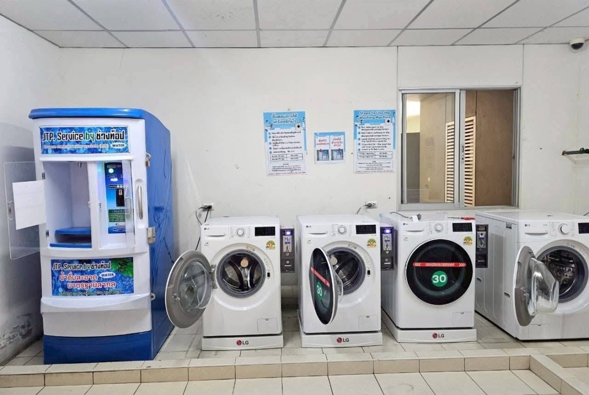 Row of LG front-loading washing machines in a laundromat, doors open, with a blue water vending machine on the left.