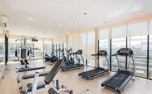 Bright modern gym with treadmills and weight machines along large windows in backlit natural light across the room.