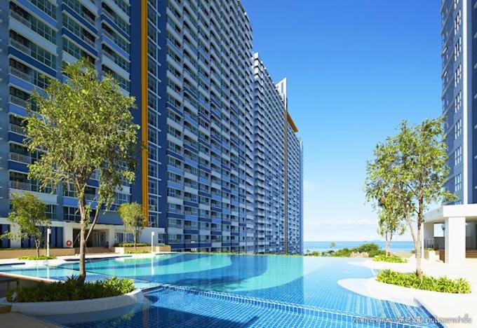 Modern high-rise apartment complex with a large outdoor pool and ocean view, promoting a resort-like vibe