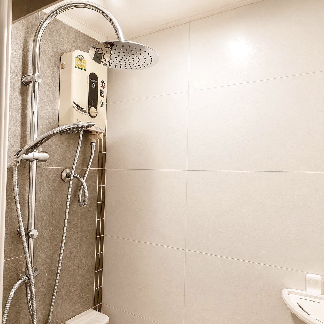 Lumpini_Park_Beach_Sale_Dlc650_10 Shower area in a tiled bathroom featuring a ceiling rain shower, a handheld shower on a chrome rail, and a wall-mounted electric water heater unit behind the shower panel