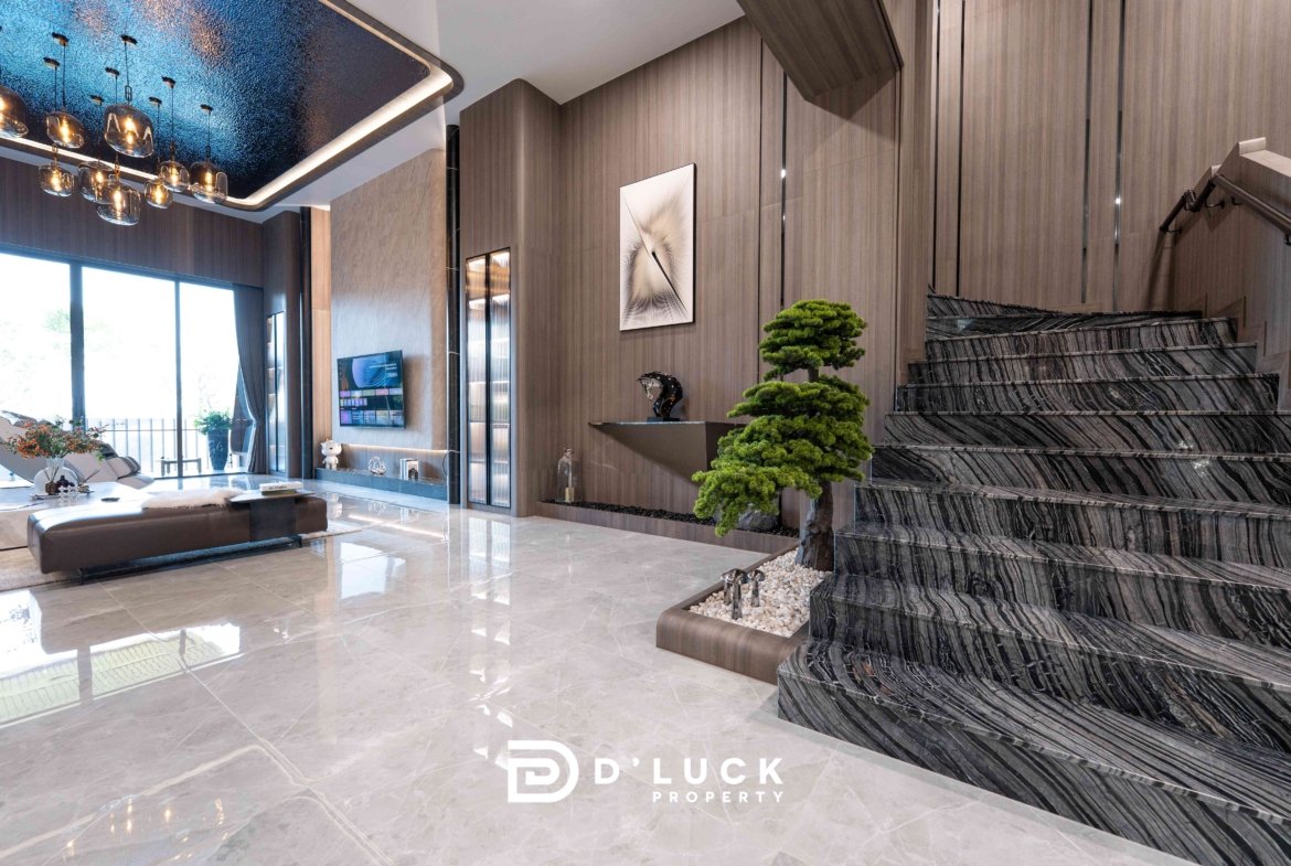 Contemporary living space with marble floors, a dramatic dark marble staircase, wall paneling, and a bonsai tree near a glass wall.