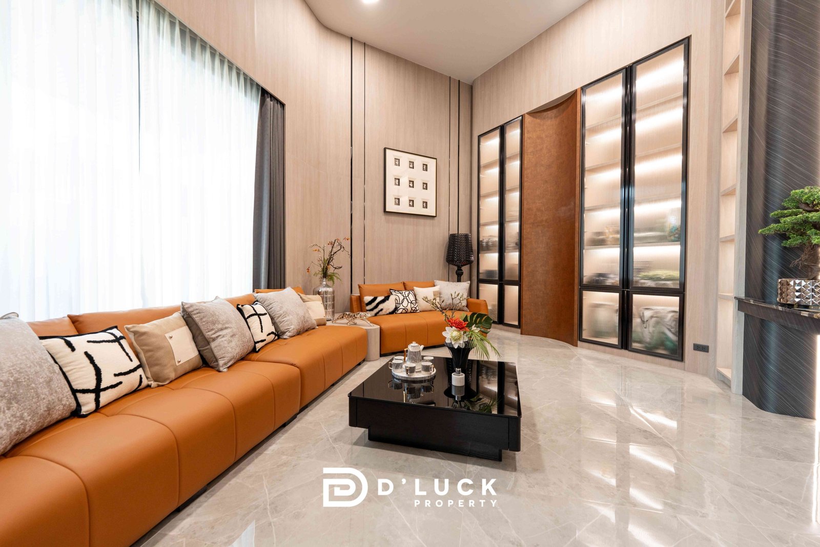 M-Mountian-M3 60 Modern living room with an orange sectional sofa, neutral cushions, and a glass coffee table in a bright showroom setting, featuring wall panels and tall glass-front cabinets.