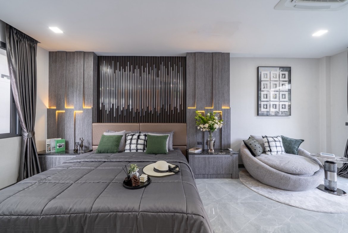 Modern gray bedroom with a tufted headboard, vertical panel wall, two nightstands, and warm accent lighting.