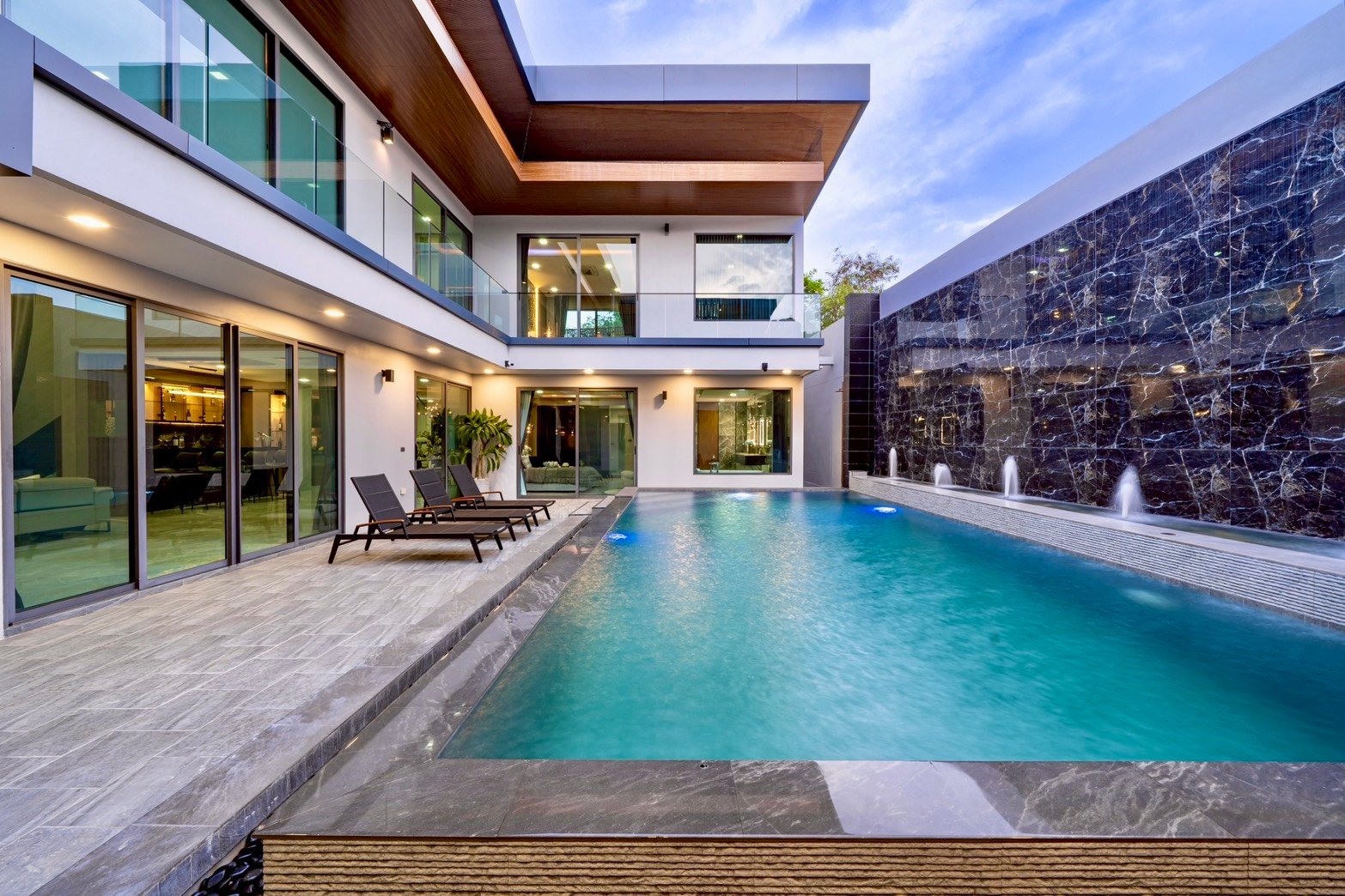 M_Mountain_Dlh518 15 Modern villa backyard with a rectangular turquoise pool, glass railings, and lounge chairs along a tiled deck