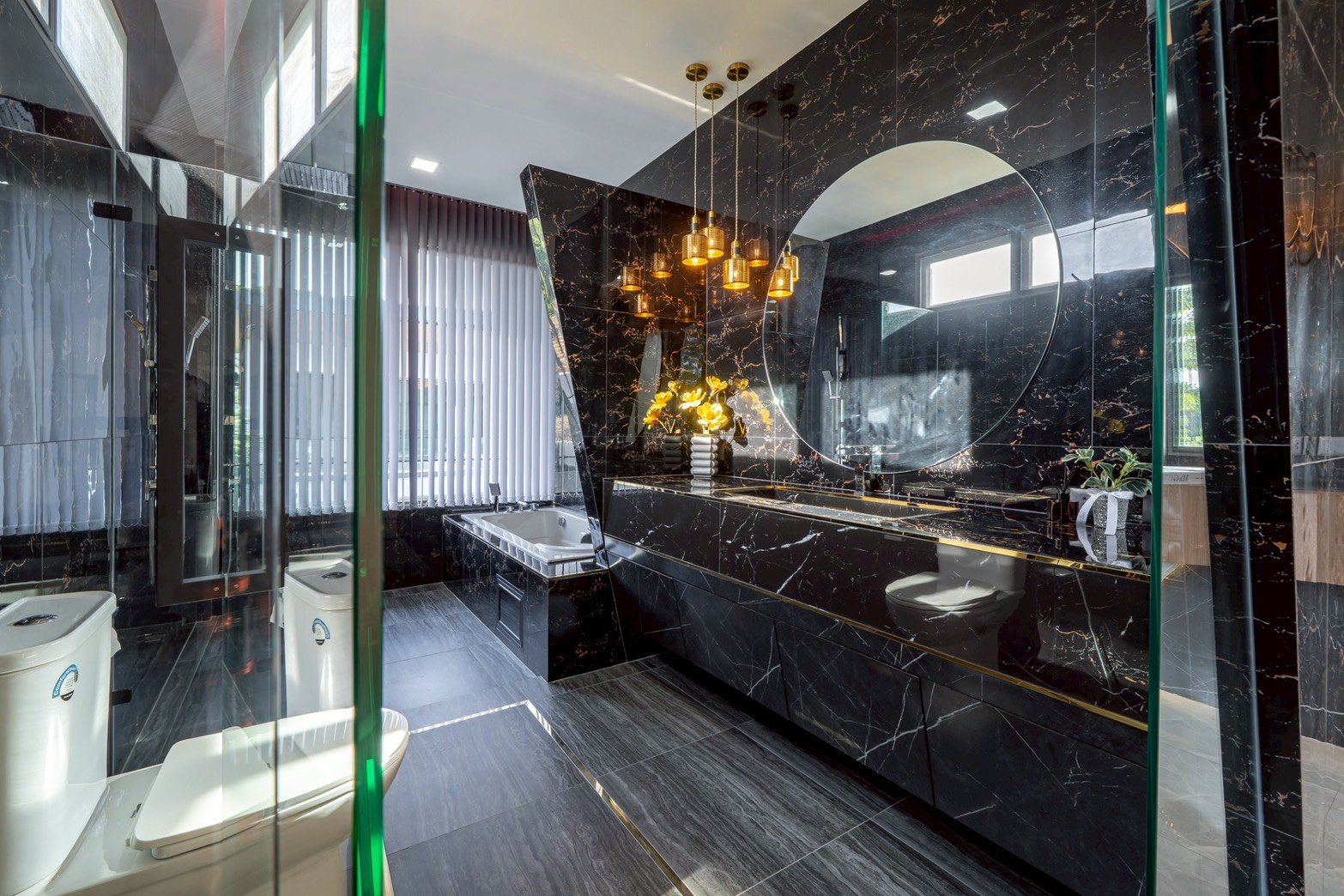 M_Mountain_Dlh518 38 Luxurious black marble bathroom with a circular mirror, dual-sink vanity, gold pendant lights, and a freestanding tub.