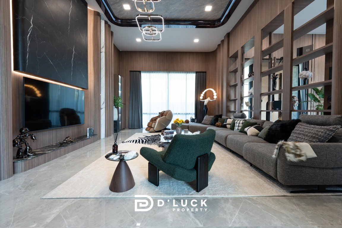 Luxurious contemporary living room with a gray sectional, green accent chair, light rug, and large window with sheer curtains.