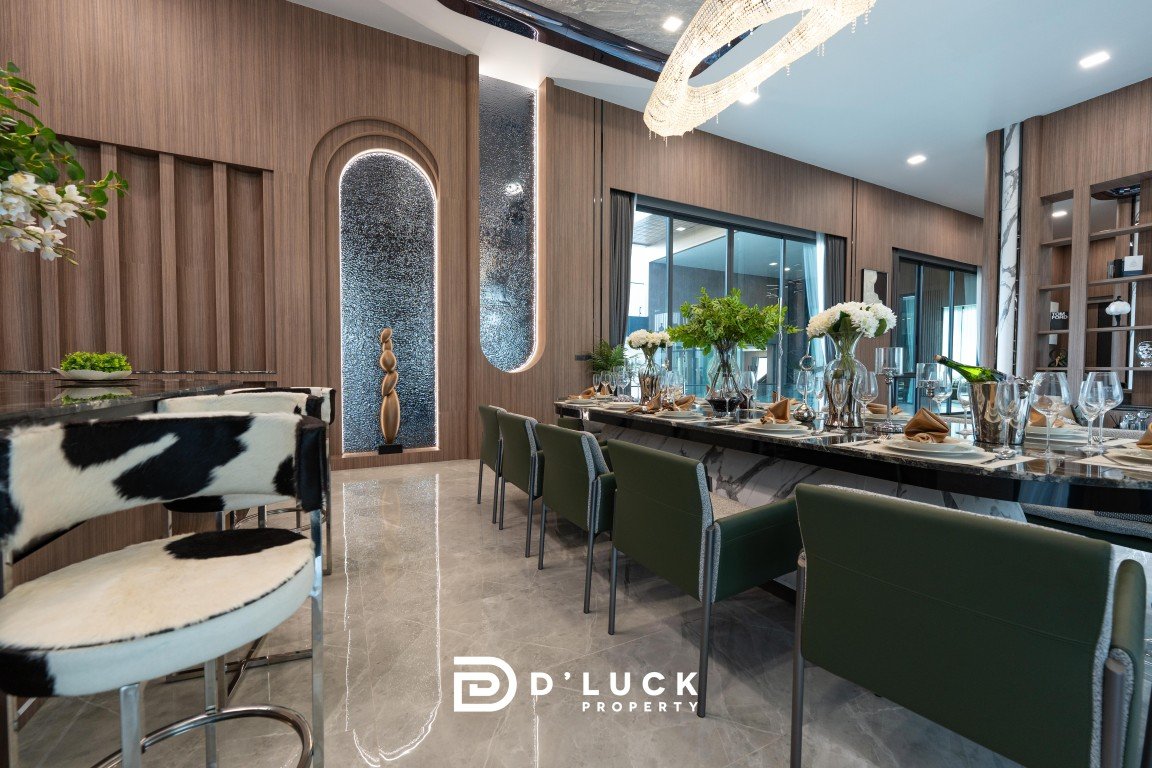 Luxurious dining room with a long marble table set for a formal meal, green chairs, and elegant flower centerpieces.