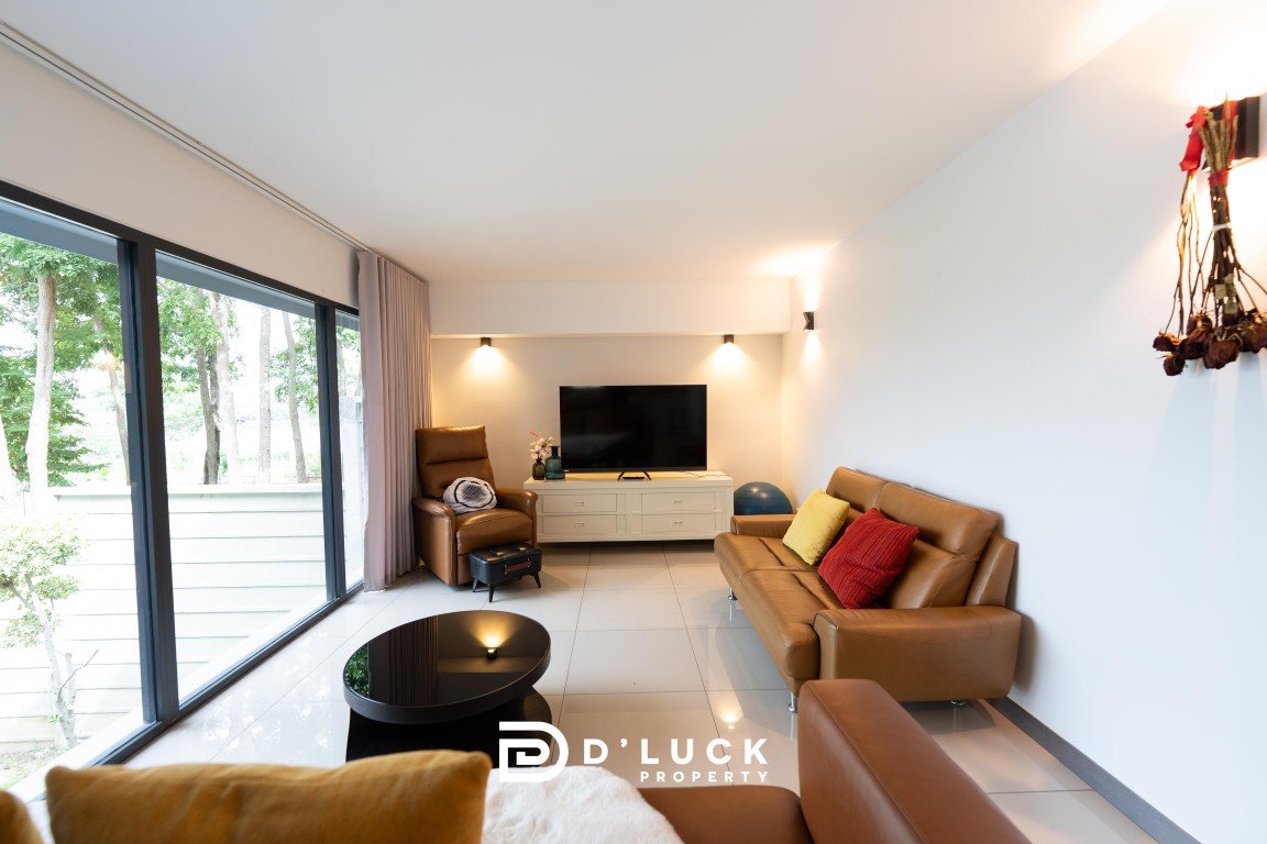 Bright living room with large glass doors, tan leather sofa set, and a TV on a white media console.