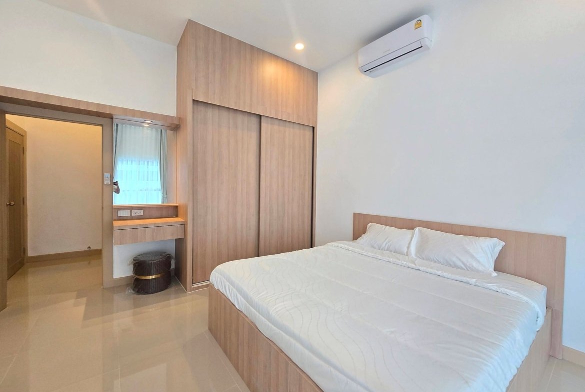 Twin beds with white quilts in a wood-paneled bedroom featuring built-in wardrobes and a wall-mounted AC unit above.