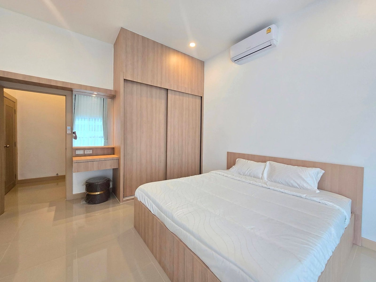 Mabprachan_Pool_Villa_Pattaya_Dlh571_9 Twin beds with white quilts in a wood-paneled bedroom featuring built-in wardrobes and a wall-mounted AC unit above.
