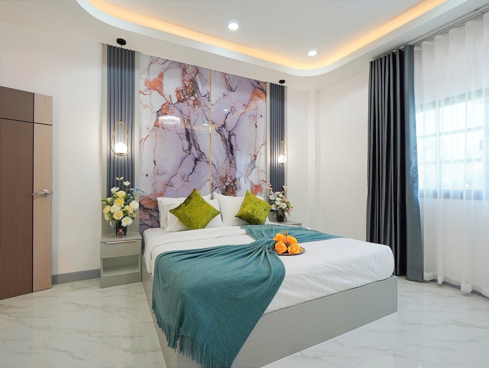 Mabprachan_Village_Pattaya_Dlh564_22 Modern hotel bedroom with a marble-pattern headboard, teal bed throw, green pillows, and fresh flowers on the nightstands.ise