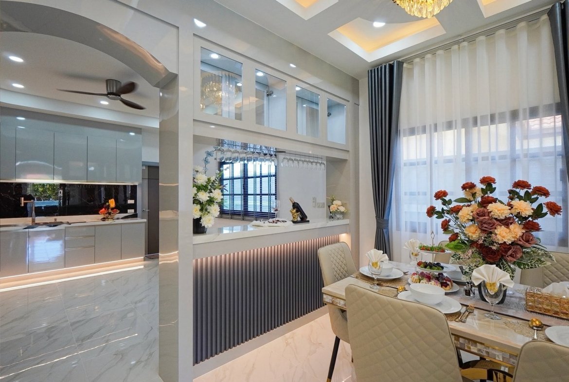 Open-concept kitchen and dining area with white cabinetry, glass-front uppers, hanging wine glasses, and a large floral centerpiece.