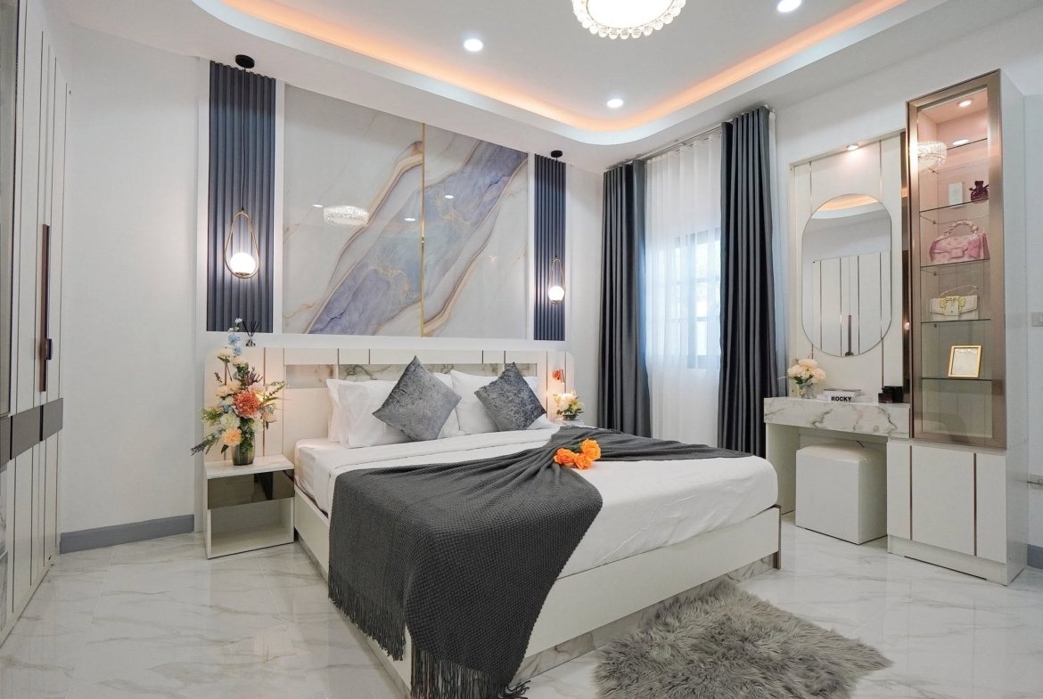 Modern showroom bedroom with white furniture, marble walls, gray bedding, chandeliers, and blue accent panels on the walls.