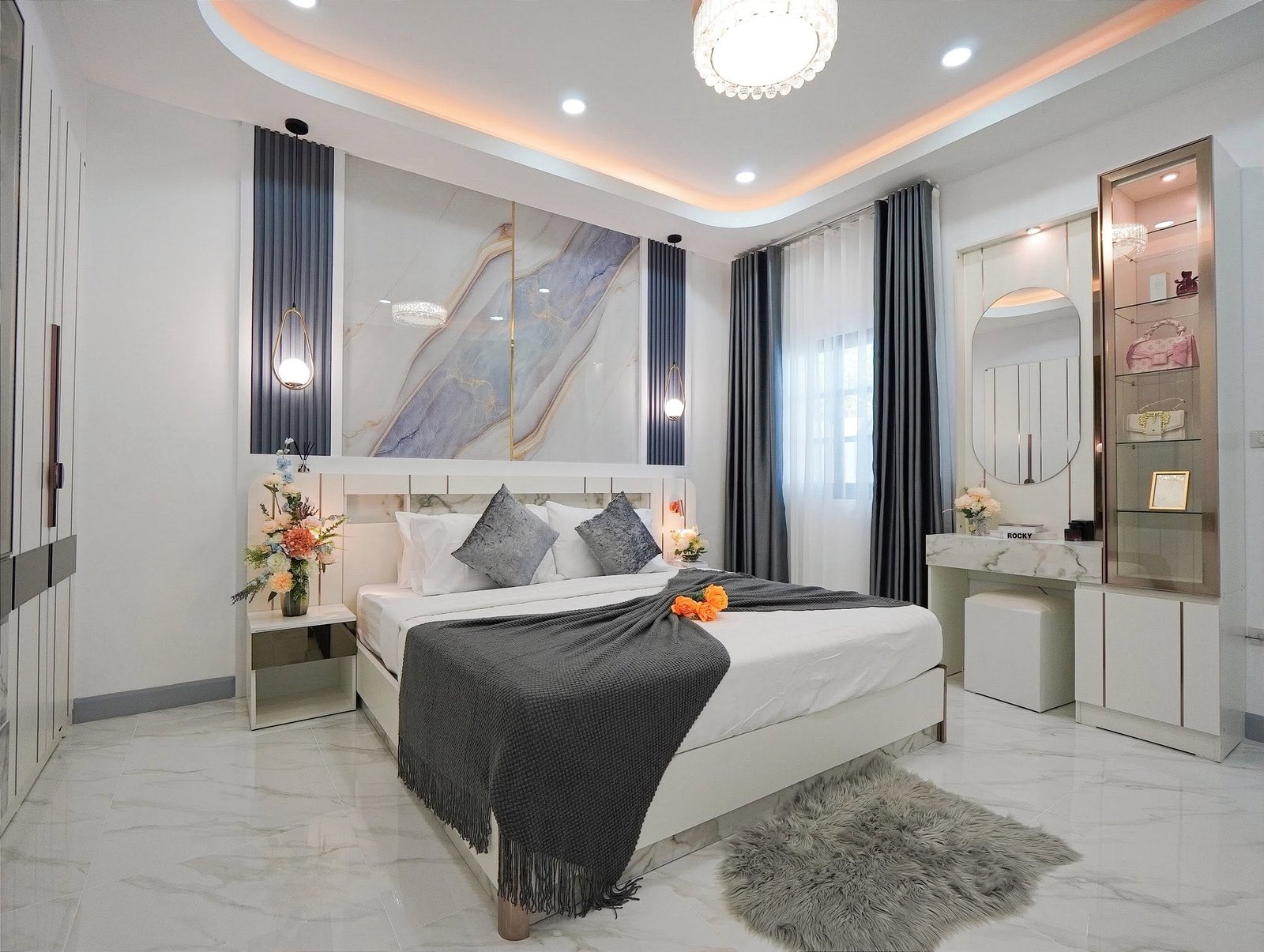 Mabprachan_Village_Pattaya_Dlh564_5 Modern showroom bedroom with white furniture, marble walls, gray bedding, chandeliers, and blue accent panels on the walls.