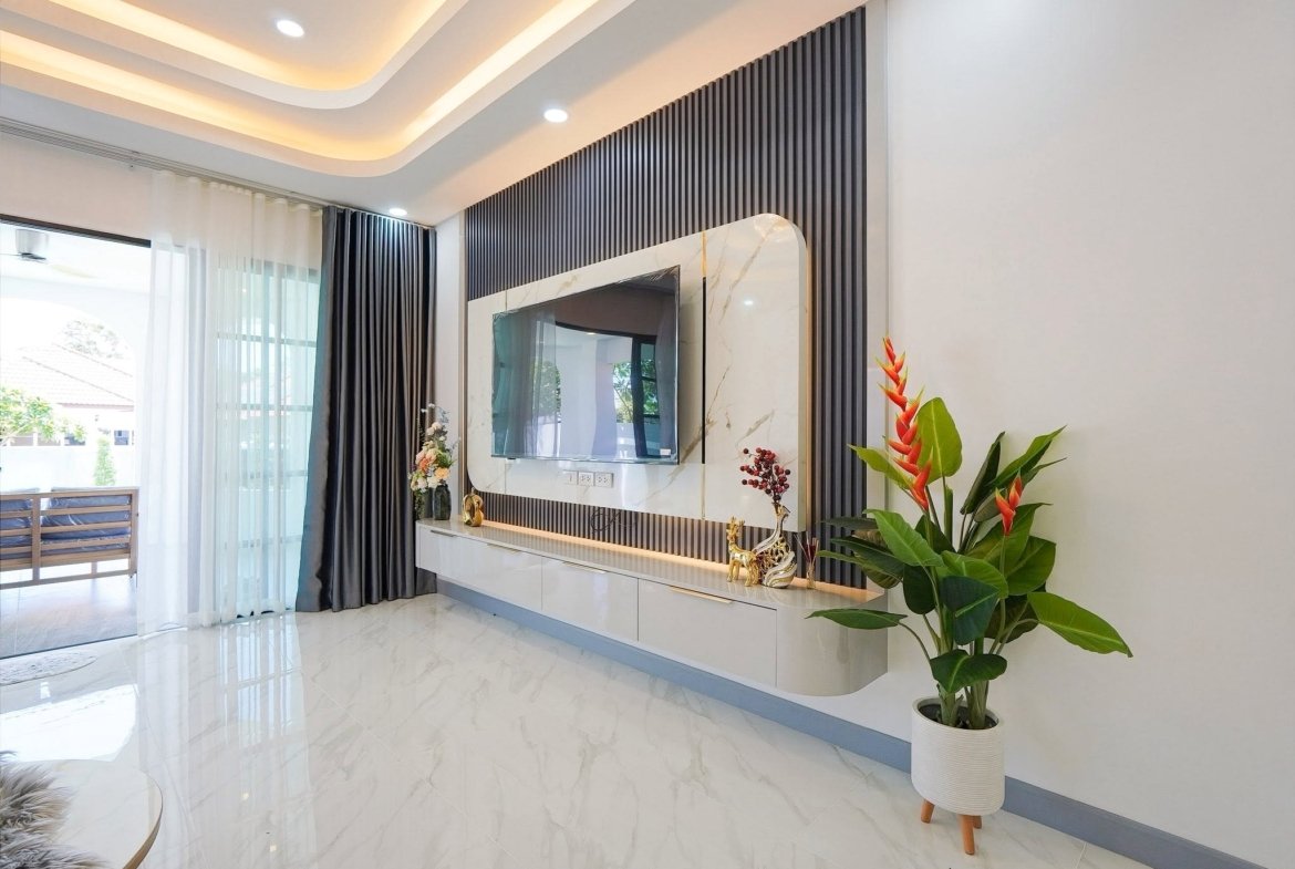 Modern living room with a wall of vertical black panels, a mounted TV, and a marble-framed console area with decor.]