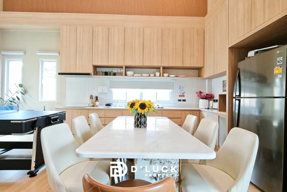 Bright kitchen and dining area with light wood cabinets, white marble table, and a sunflower centerpiece