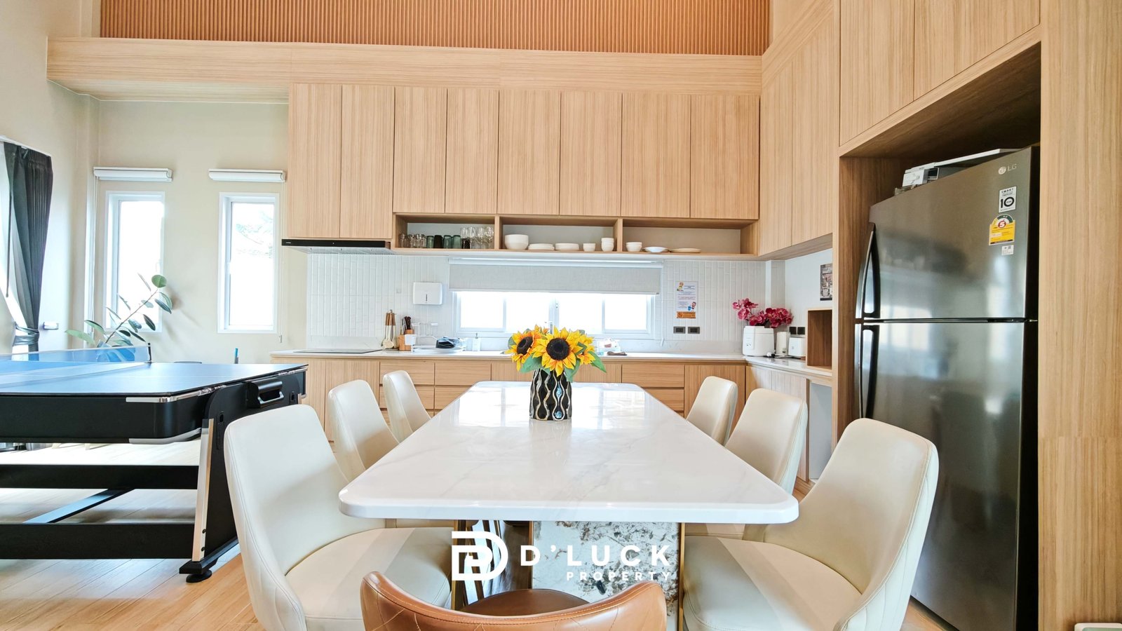 Bright kitchen and dining area with light wood cabinets, white marble table, and a sunflower centerpiece