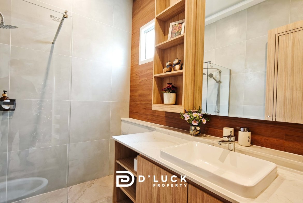 Modern bathroom featuring a glass shower enclosure, light gray tiled walls, and a white marble countertop with a rectangular sink.